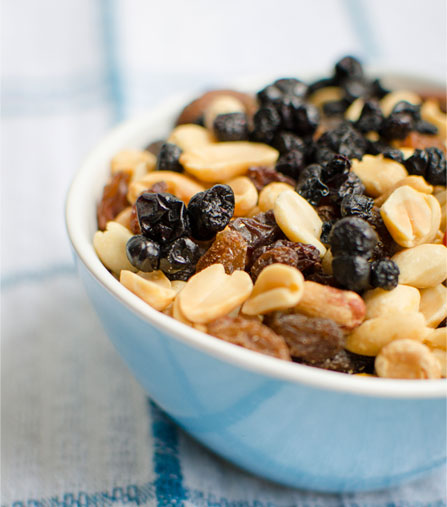 A bowl of assorted nuts and dried fruit, topped with chewy wild blueberries.